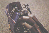 Fixé sur une potence assez reculée, le guidon a une forme peu orthodoxe pour une moto de course. Les poignées sont très verticales et la position très ramassée.