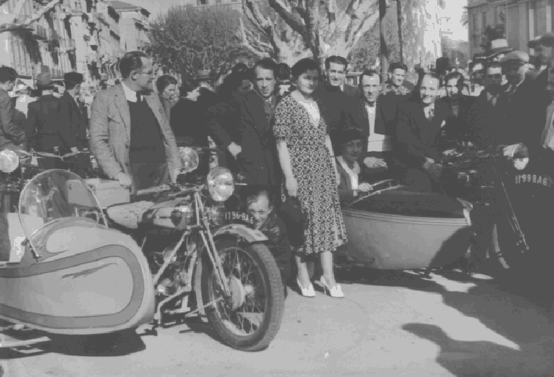 Antoine Peirano est accroupi près de la roue avant du premier sidecar.